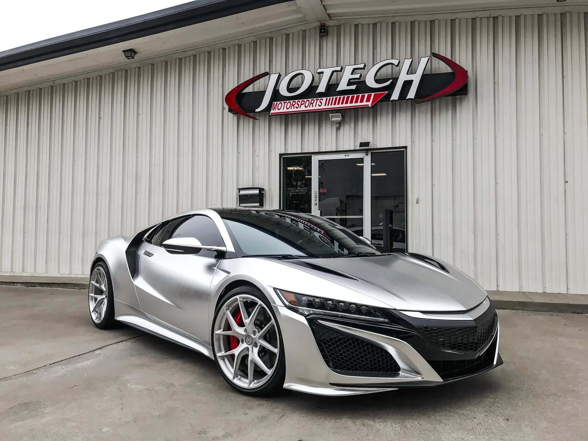 Silver Acura NSX sports car with custom HRE wheels parked outside Jotech Motorsports performance tuning shop.