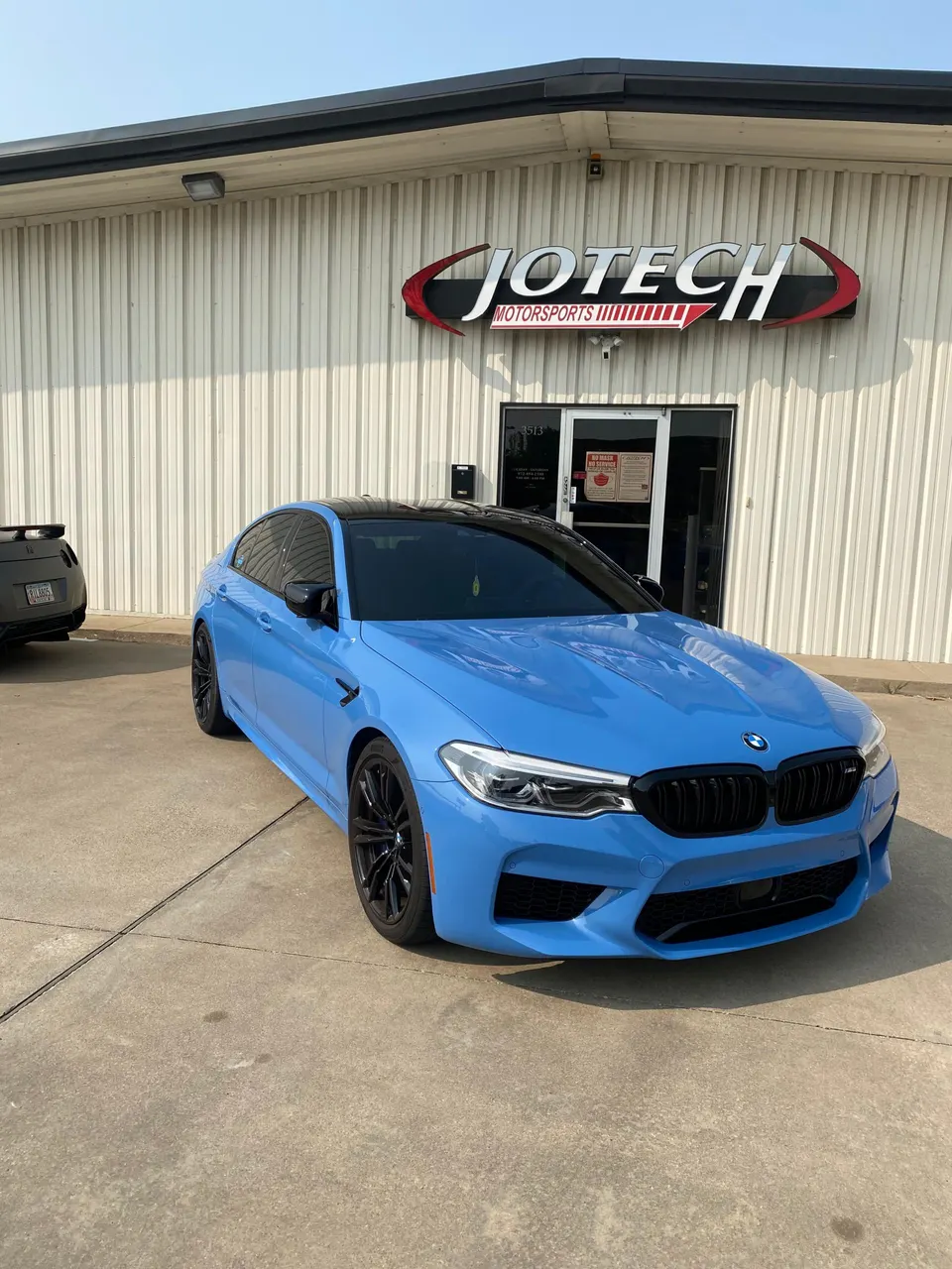 Blue BMW M5 performance sedan parked outside Jotech Motorsports tuning shop