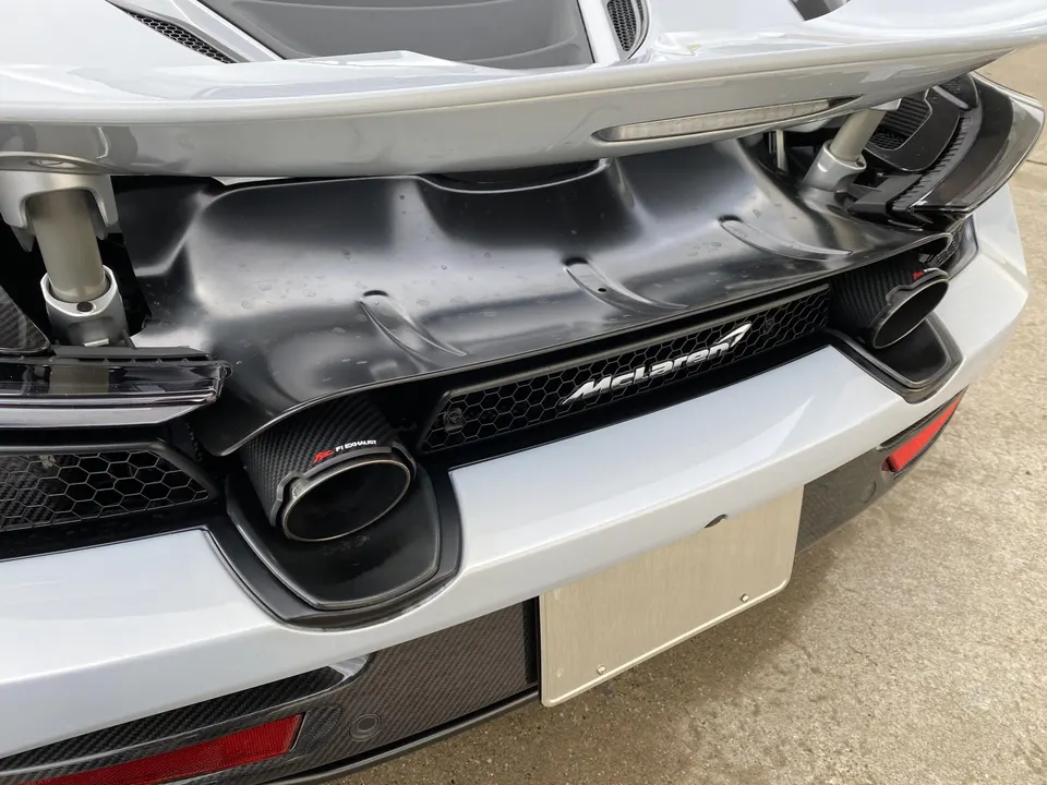 Close-up of a McLaren's rear with Akrapovic carbon fiber exhaust tips and a prominent McLaren logo.