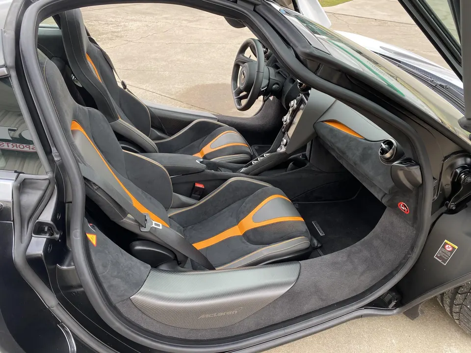 McLaren interior with black and orange Alcantara seats, carbon fiber door sills, and dashboard.