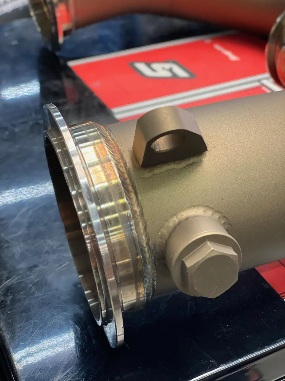 Close-up of a high-performance exhaust pipe with a visible weld and flange, ready for installation.