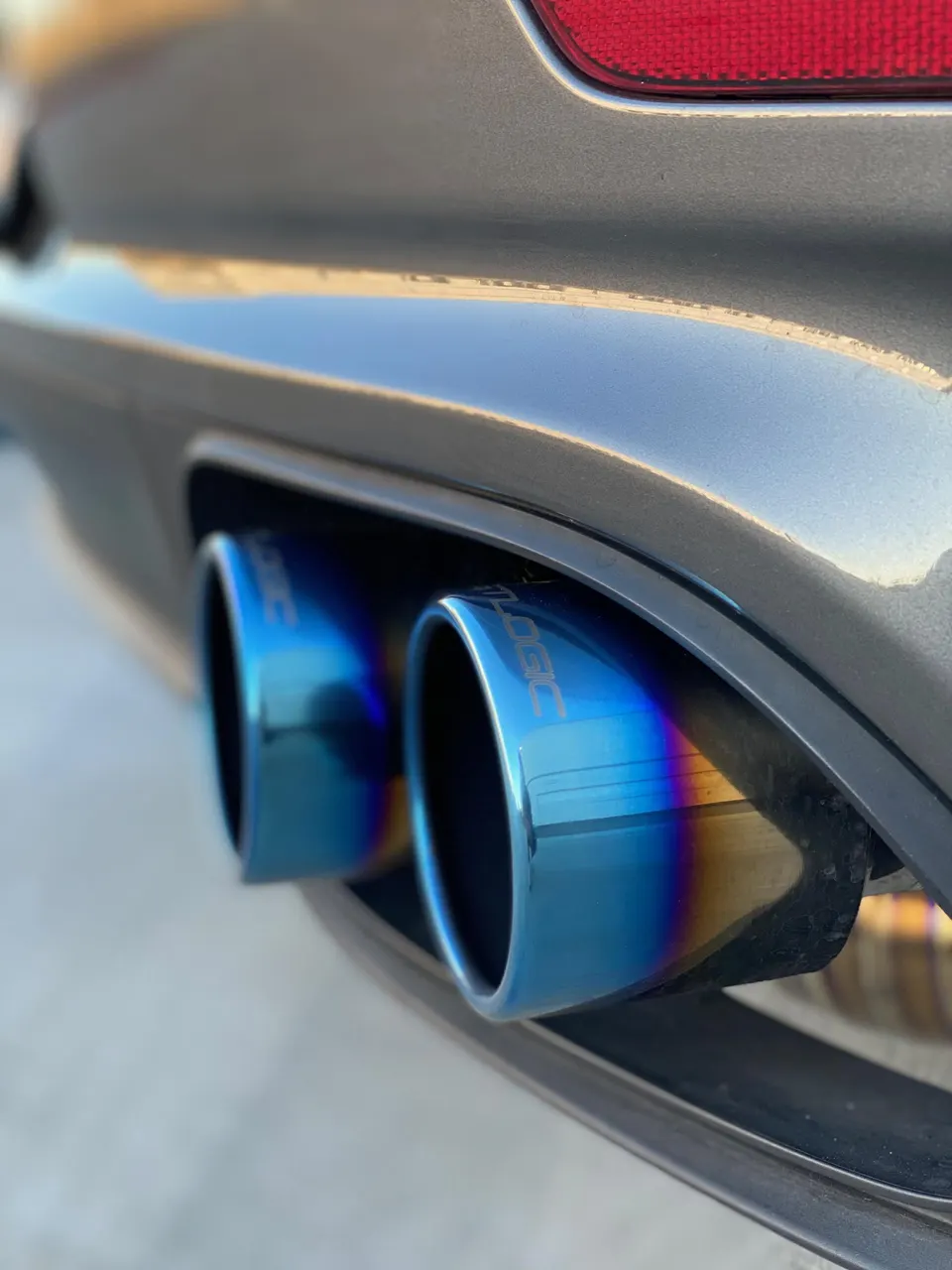 Close-up of blue titanium exhaust tips on a performance car's rear bumper.