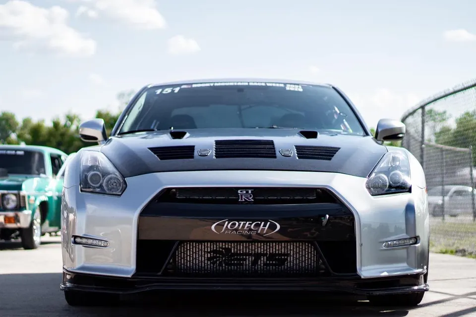 Front view of a silver Nissan GT-R with a carbon fiber hood and Jotech Racing intercooler at a track event.