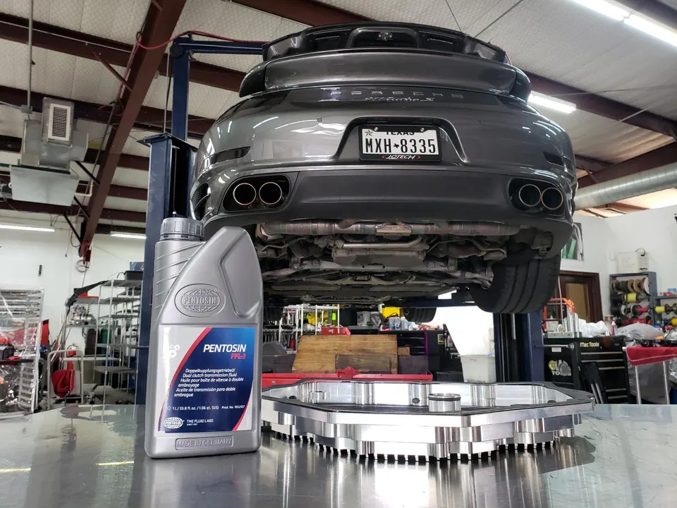 A grey Porsche 911 on a lift in a Jotech Motorsports shop, with Pentosin transmission fluid and an aftermarket transmission pan.