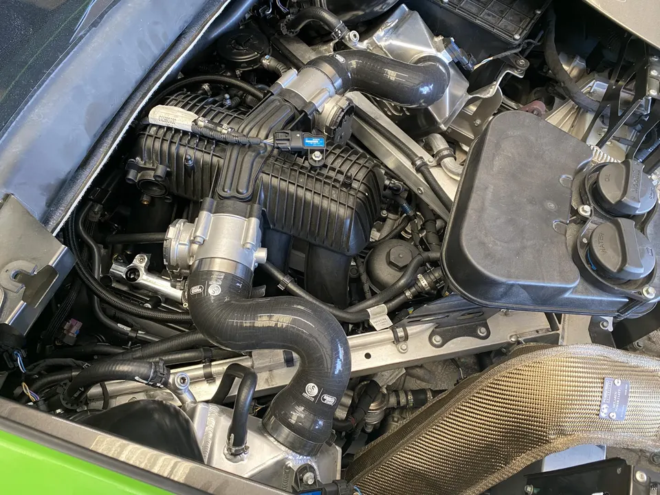 Detailed view of a performance car's engine bay, showcasing boost piping, intake manifold, and carbon fiber components.