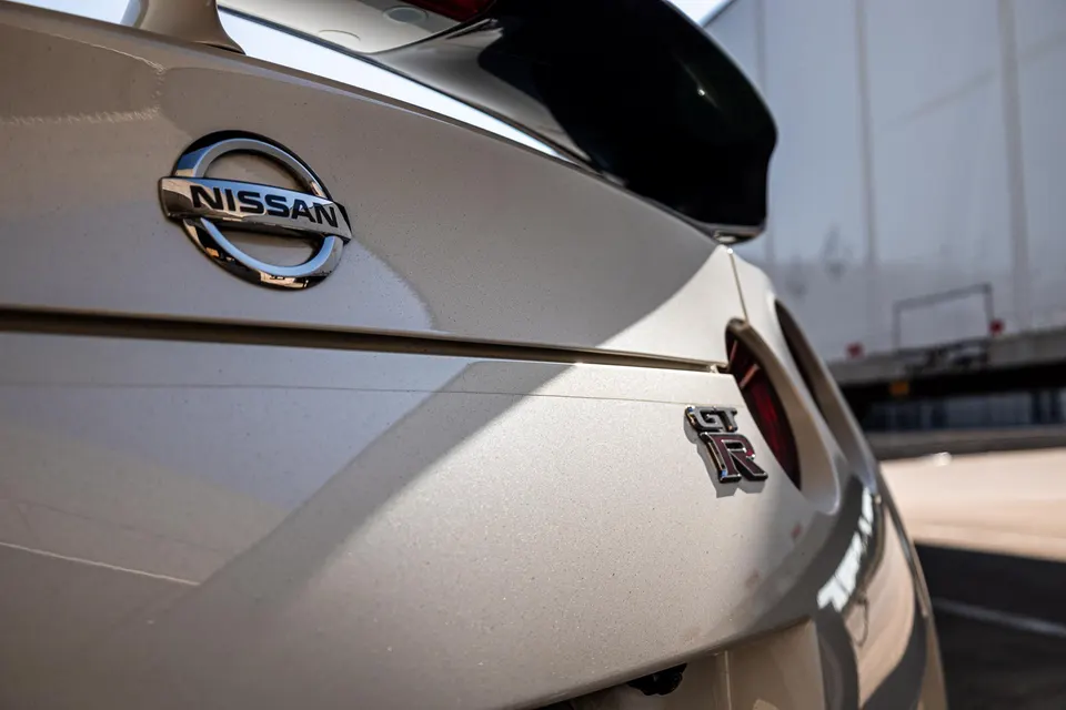 Close-up of the rear of a white Nissan GT-R, showing the Nissan and GT-R badges and a black rear wing.