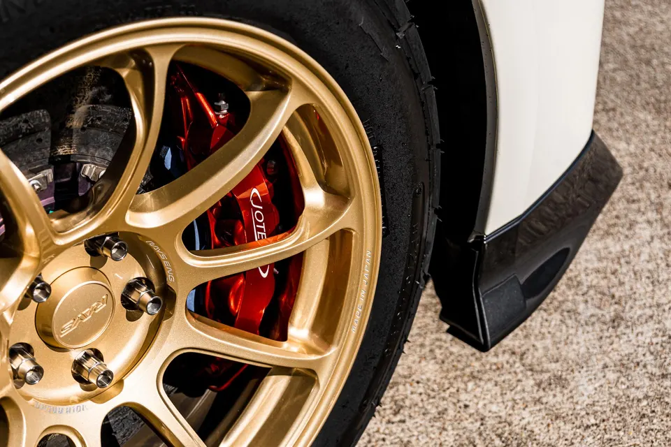 Close-up of a gold Rays wheel with red Brembo calipers and a track tire on a performance car.