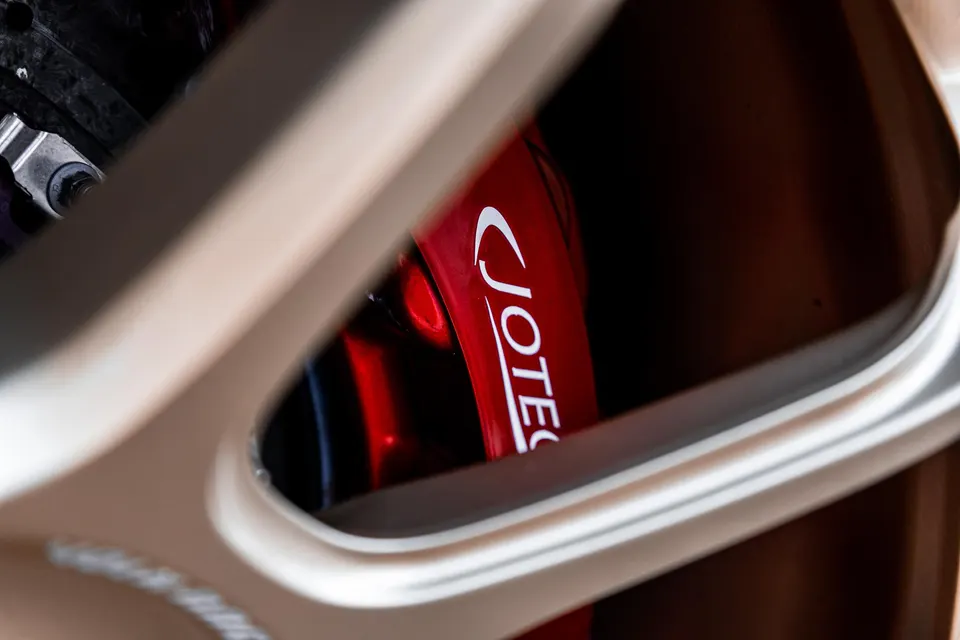 A close-up shot of a red Jotech brake caliper visible through a bronze multi-spoke wheel.