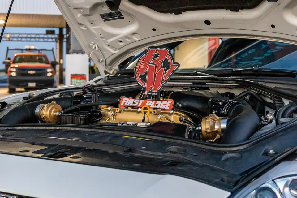 Close-up of a Nissan GT-R engine bay with gold turbo components and a 'First Place' trophy.