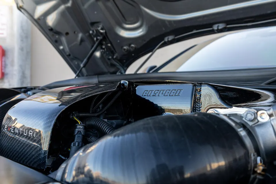Close-up of a car's engine bay featuring an Eventuri carbon fiber intake and GoSpeed charge pipe.