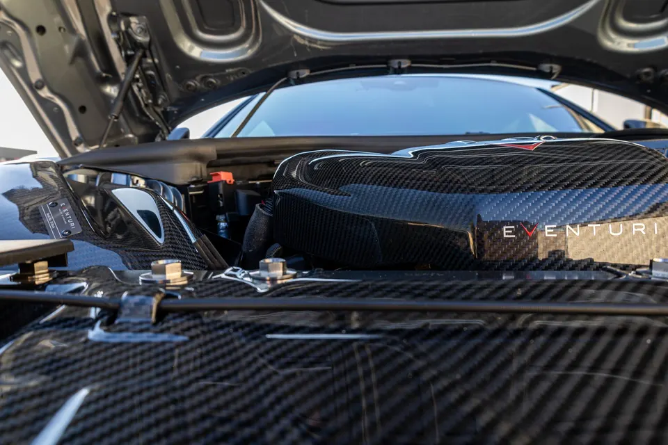 A close-up of a car's engine bay featuring an Eventuri carbon fiber intake system.