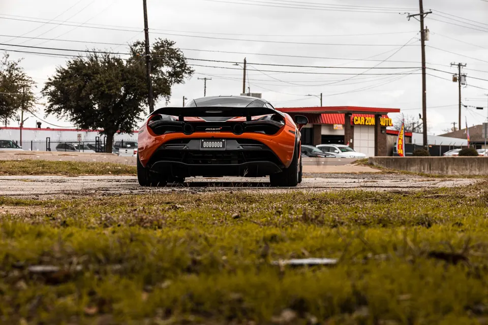 Orange McLaren 720S parked outdoors, showcasing its rear wing and diffuser.
