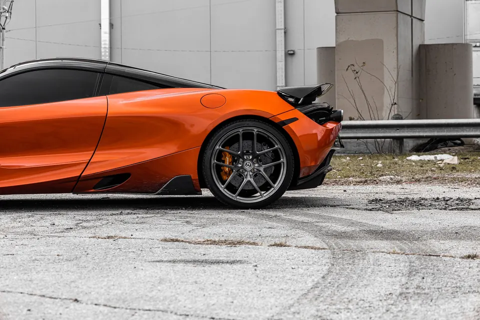 Side view of an orange McLaren 720S with HRE aftermarket wheels and carbon fiber aerodynamic parts.