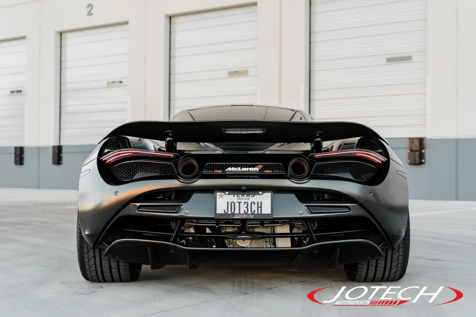 A black McLaren 720S from the rear, showcasing its active rear wing, carbon fiber diffuser, and dual exhaust tips.
