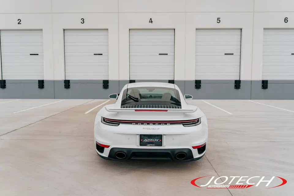 Rear view of a white Porsche 911 Turbo S parked in front of several garage doors at Jotech Motorsports.