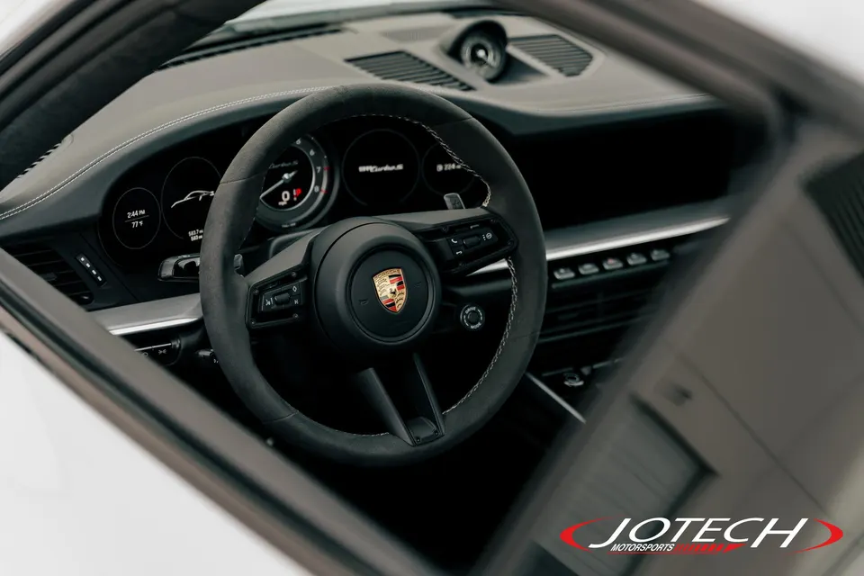 Detailed view of a Porsche interior, showcasing the steering wheel, dashboard, and instrument cluster.