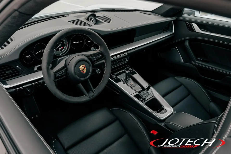 Interior view of a modern Porsche with a black leather dashboard, steering wheel, and center console.