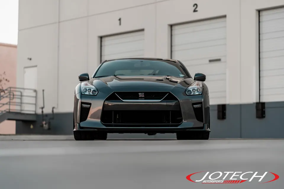 Front view of a grey Nissan GT-R R35 parked in front of a building, showcasing its aggressive styling.