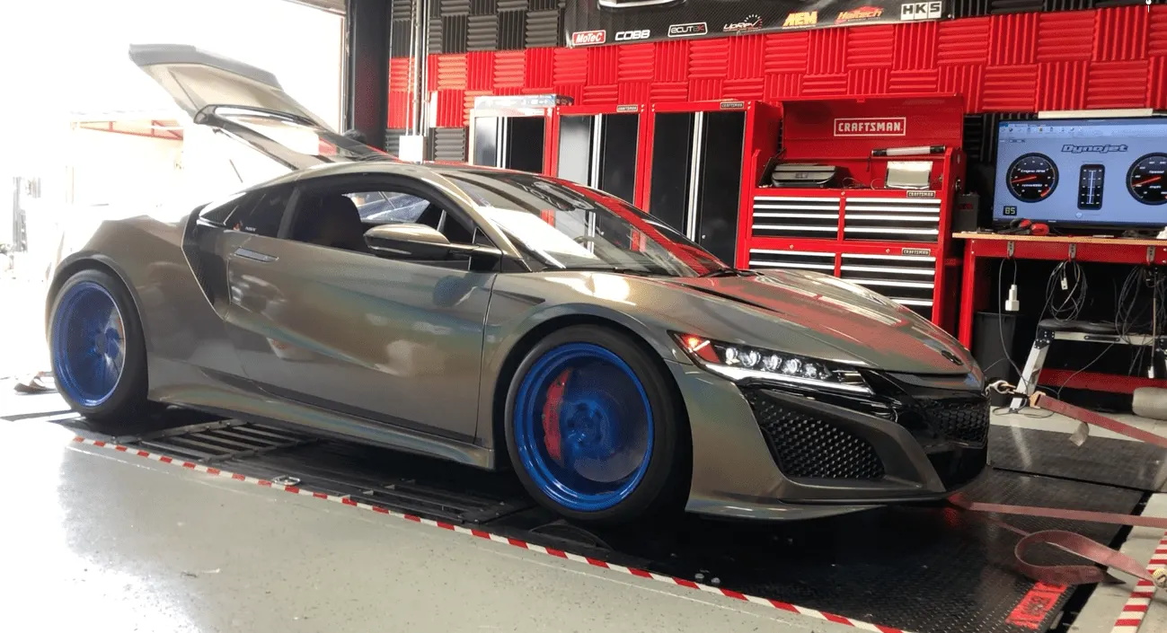 A grey Acura NSX on a Dynojet dynamometer with blue wheels, undergoing performance tuning at a shop.