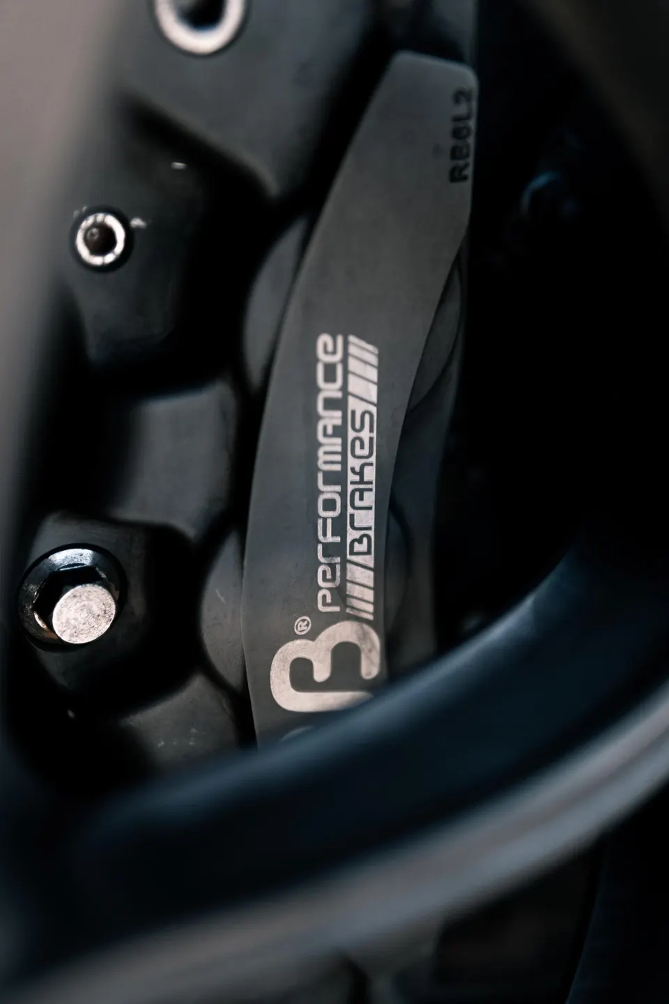 Close-up of a dark grey performance brake caliper with 'B Performance Brakes' logo and 'RB6L2' text.