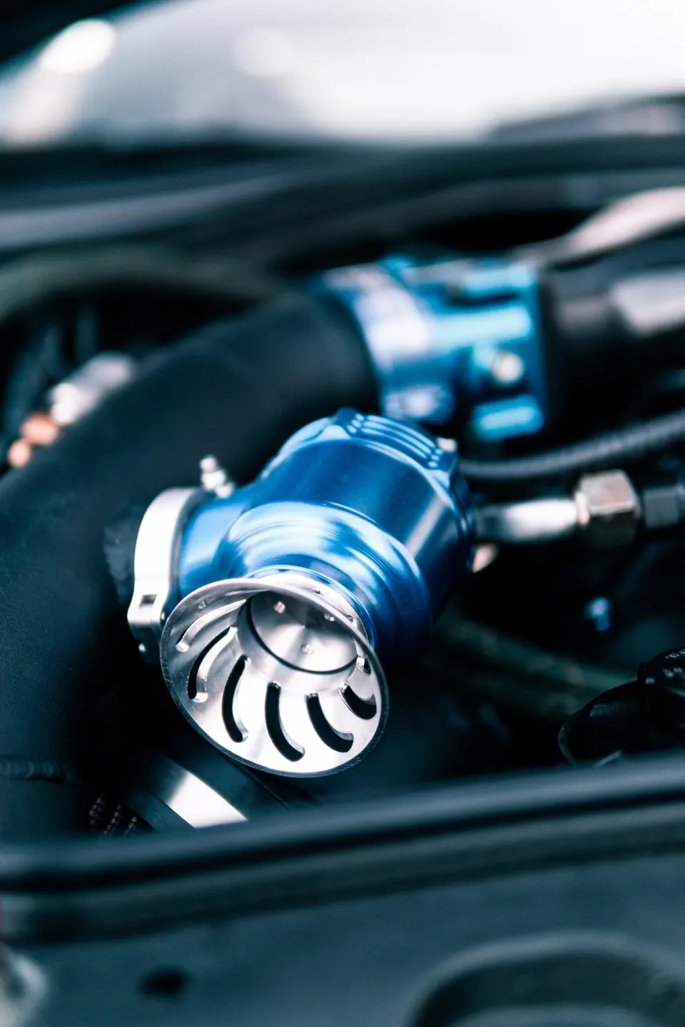Close-up of a blue aftermarket blow-off valve in a performance car's engine bay