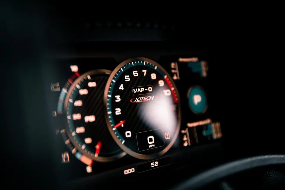 Close-up of a Jotech digital dashboard displaying gauges and vehicle information, including speed and RPM.