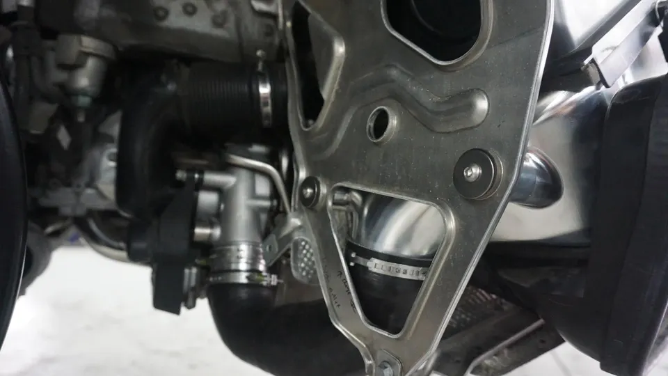 A close-up view of a car's engine bay, showing a boost pipe, clamps, and a metal bracket.