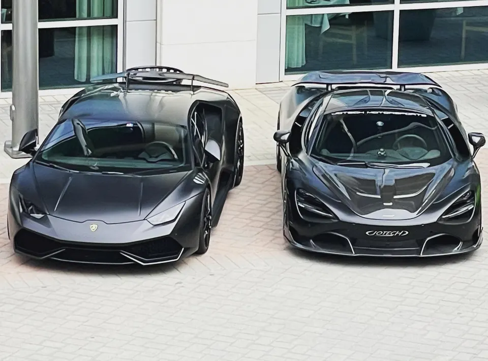 Two modified supercars, a matte grey Lamborghini Huracan and a dark grey McLaren 720S, parked side by side.
