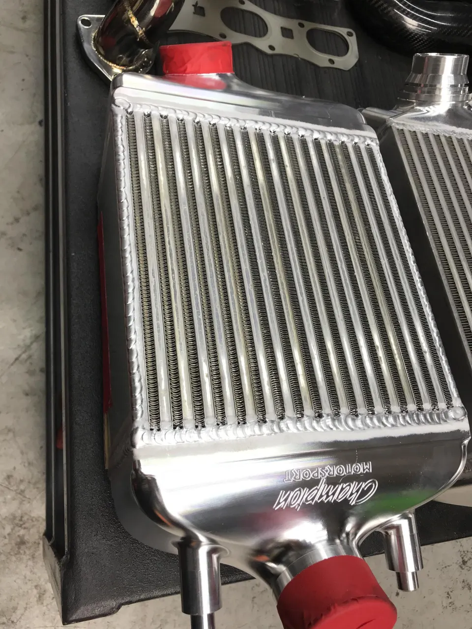 Close-up of a Champion Motorsport aluminum intercooler on a workbench, a key component for forced induction systems.