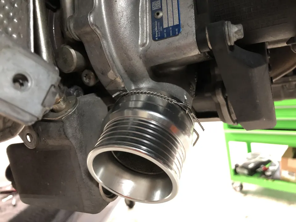 Close-up of a turbocharger exhaust outlet with a v-band clamp in a performance shop.