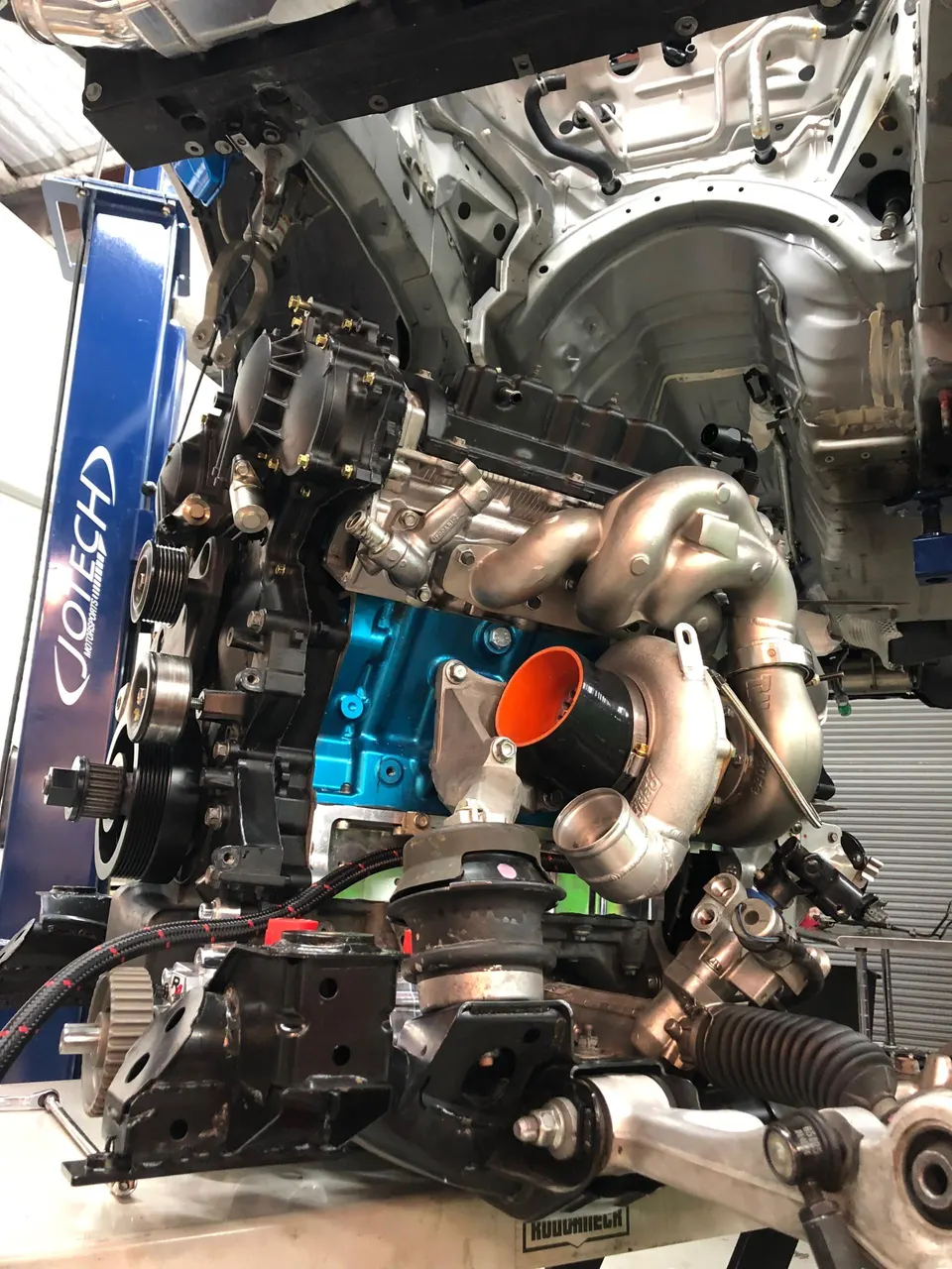 High-performance engine with a large turbocharger and custom exhaust manifold being assembled at Jotech Motorsports.