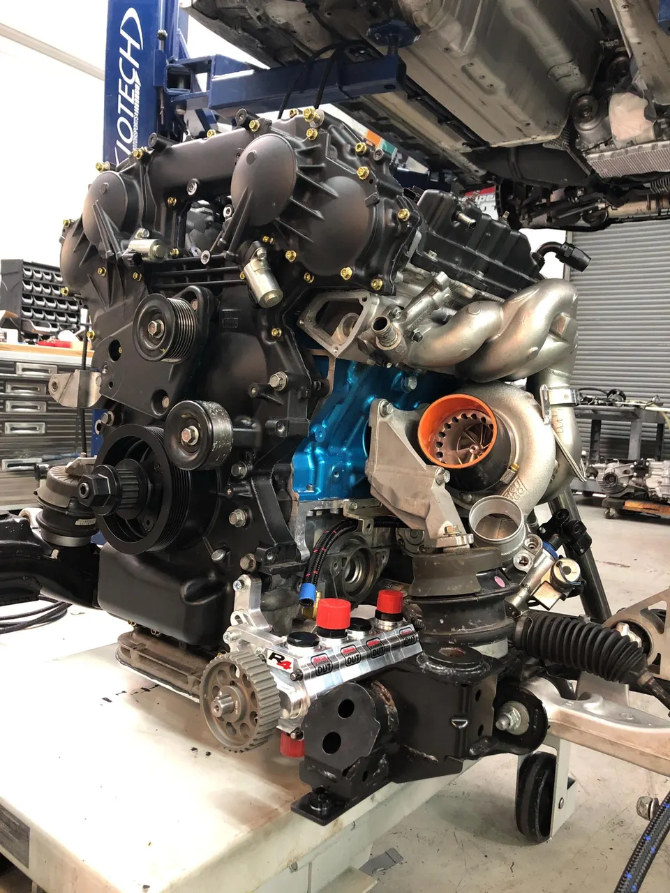 Built performance engine assembly with a large turbocharger and aftermarket fuel system components on a stand in a Jotech Motorsports shop.