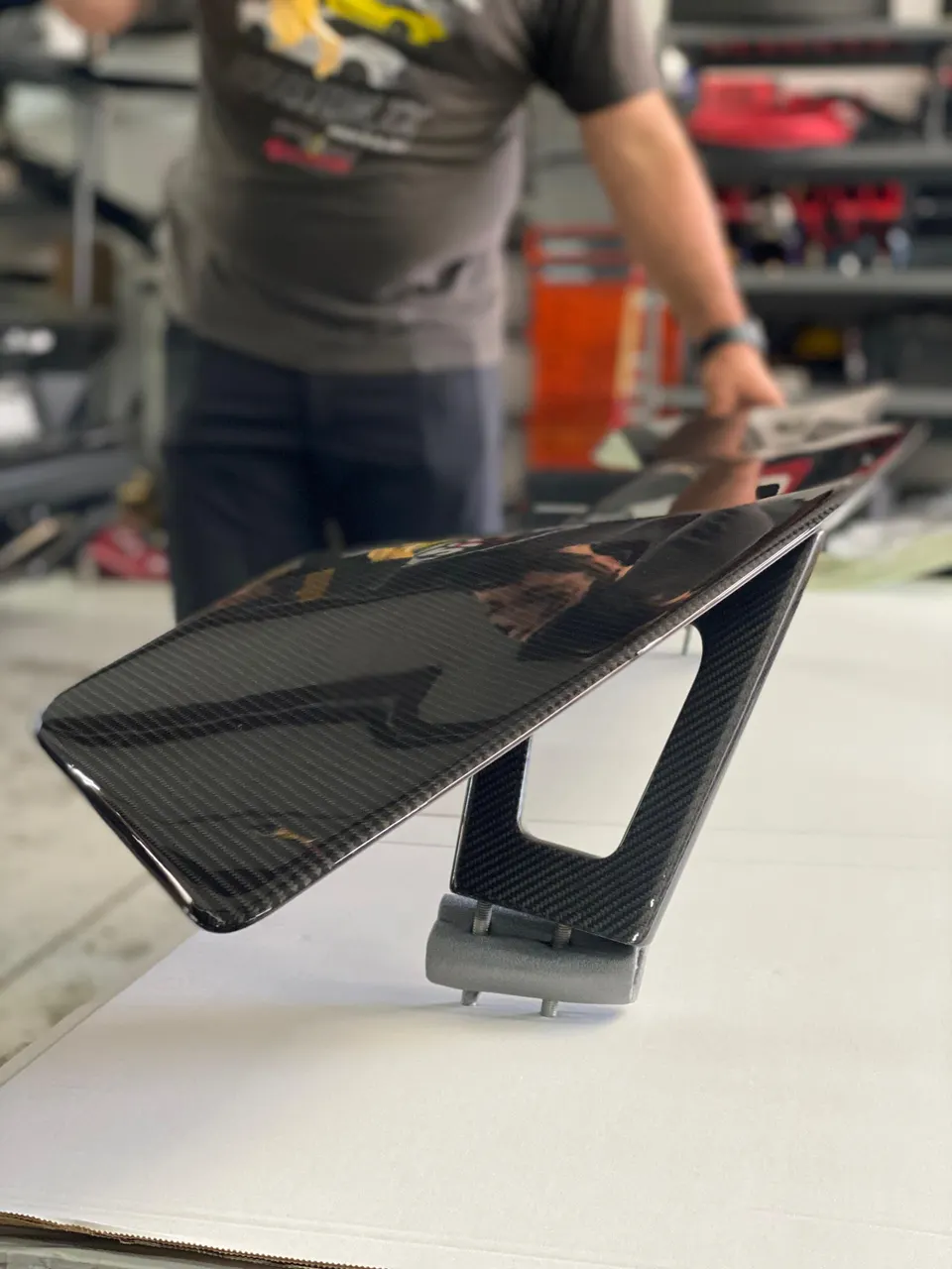 Close-up of a carbon fiber rear wing in a performance shop.