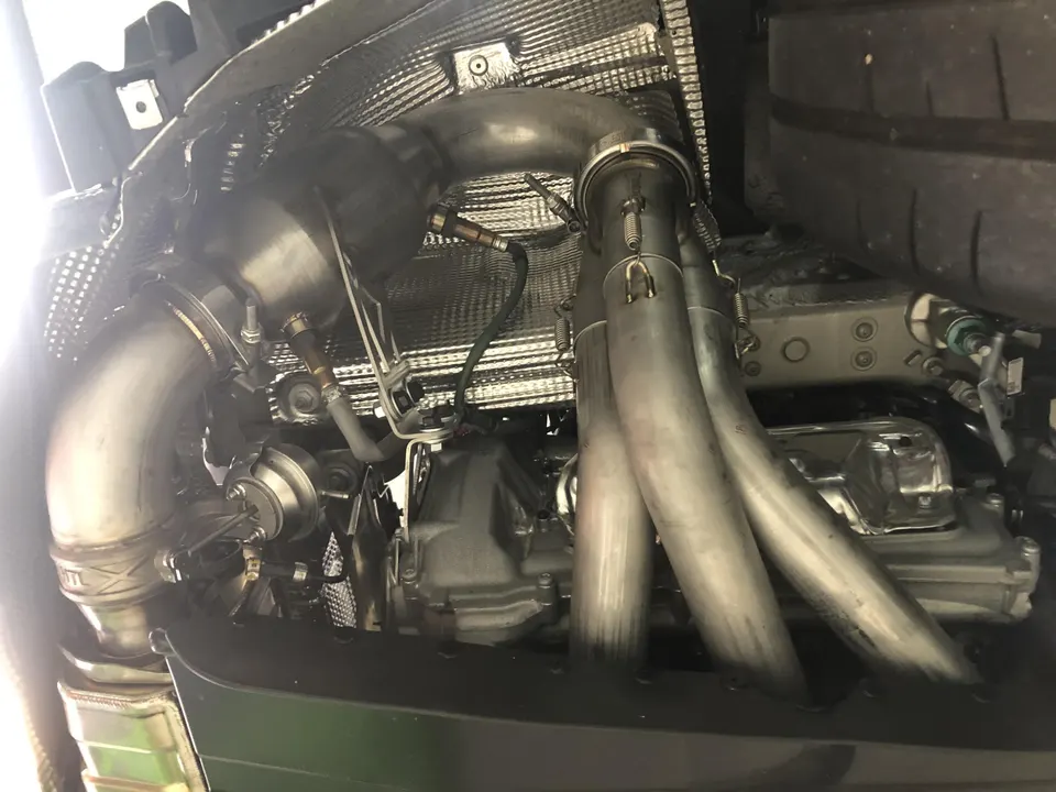 Close-up of a high-performance engine bay featuring aftermarket turbocharger, wastegate, and stainless steel exhaust headers.
