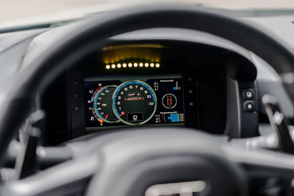 A close-up of a Jotech digital dashboard displaying performance data and gauges in a car's interior.