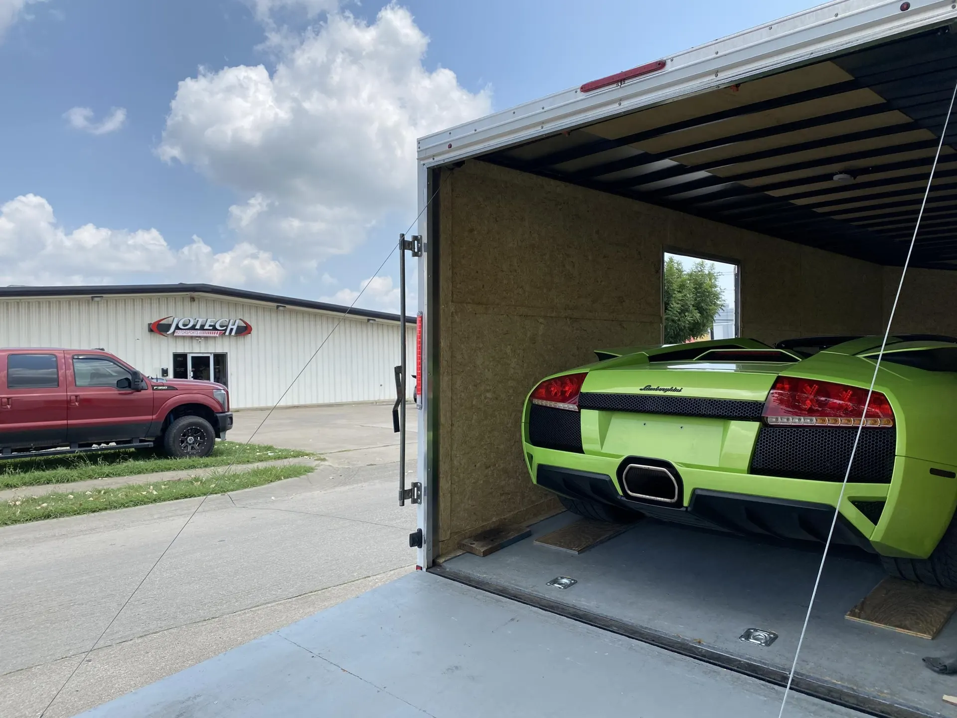 Lime green Lamborghini Murcielago being unloaded from a car trailer at Jotech Motorsports shop.