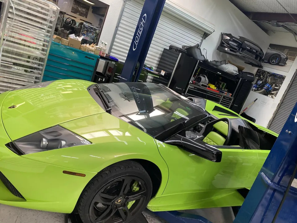 A lime green Lamborghini Murcielago convertible on a lift in a Jotech Motorsports performance tuning shop.