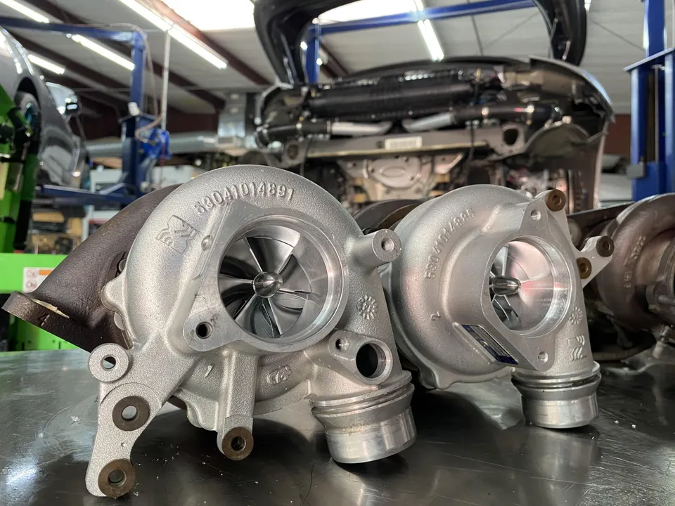Two new turbochargers on a workbench in a performance tuning shop, ready for installation on a high-performance car.