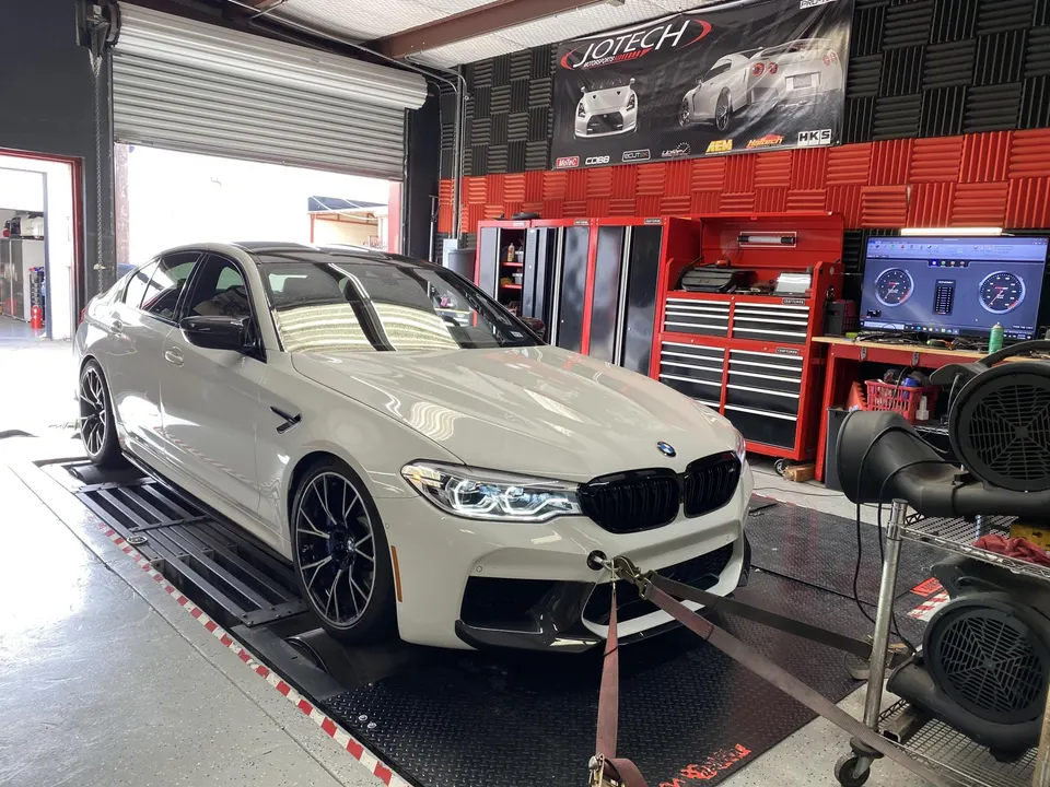White BMW M5 strapped to a dynamometer for performance tuning at Jotech Motorsports.