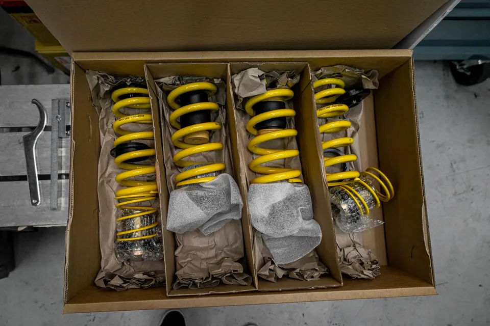 New yellow suspension coilovers and springs in their packaging, ready for installation in a performance car.