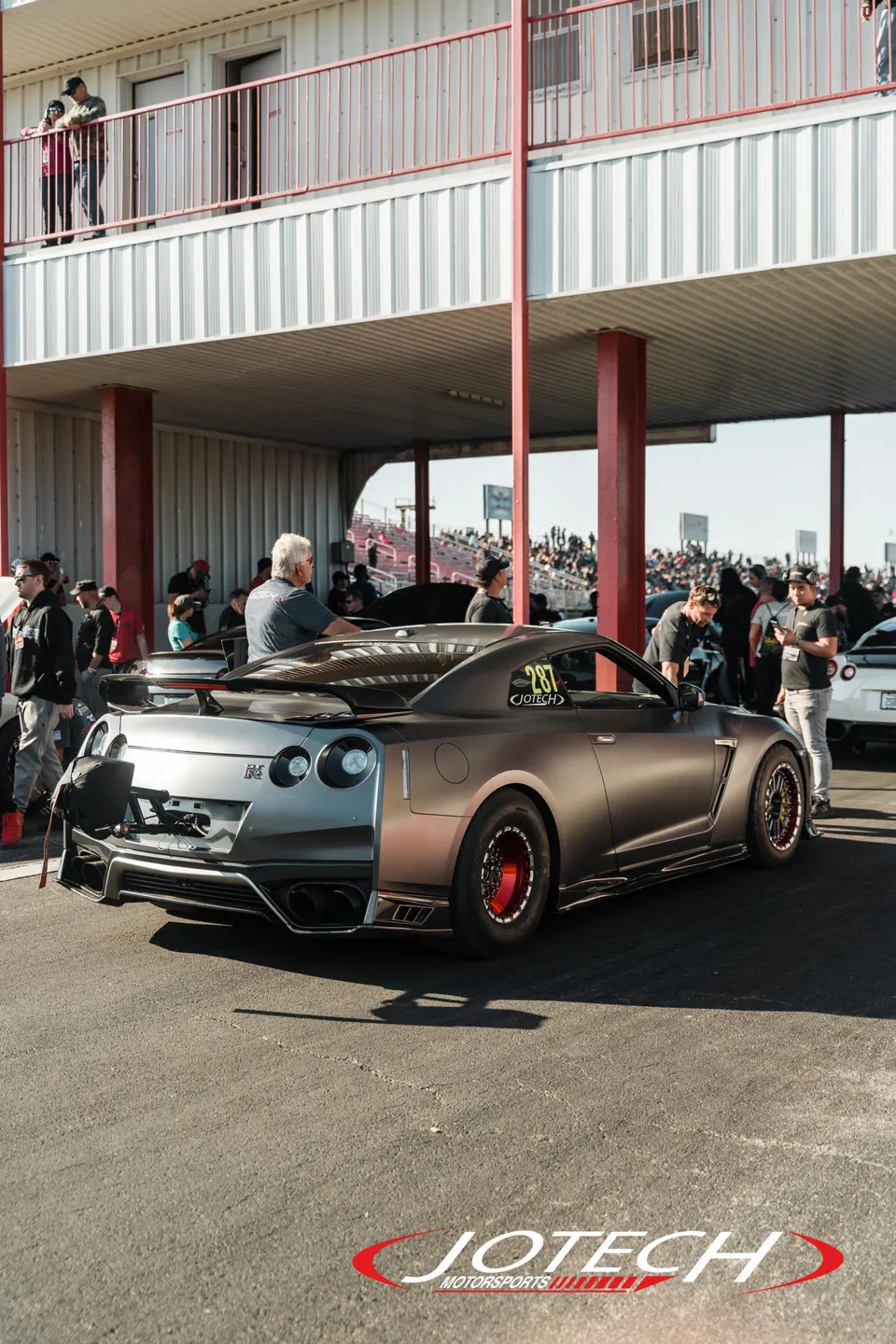 A modified Nissan GT-R with drag wheels and a parachute mount at a drag strip.