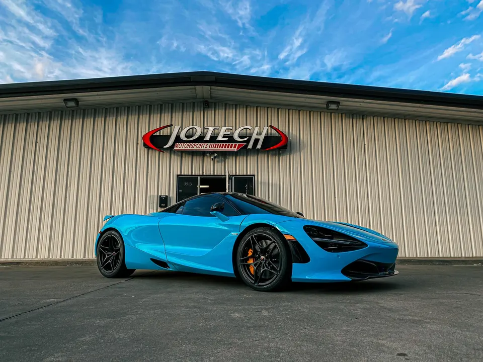 Blue McLaren 720S supercar parked in front of the Jotech Motorsports performance tuning shop building.