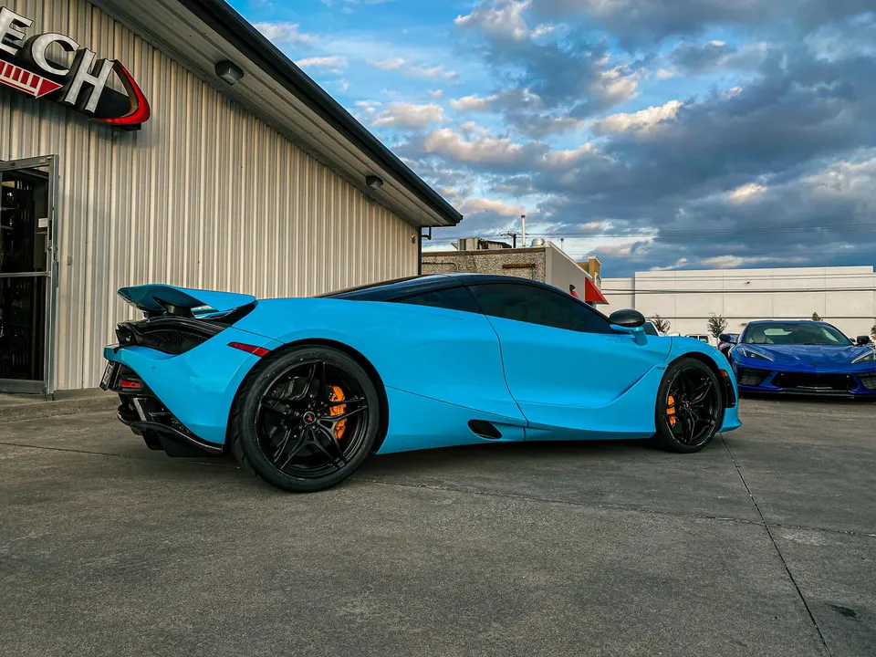 Light blue McLaren 720S and blue Corvette C8 parked outside Jotech Motorsports performance shop.