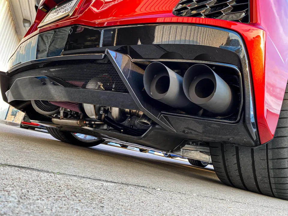 Rear view of a red Corvette showcasing aftermarket exhaust tips, a visible turbocharger, and a performance rear diffuser.