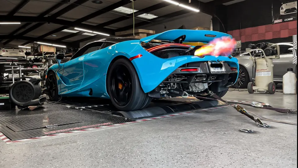 A blue McLaren 720S on a dyno, shooting flames from its exhaust during a performance tuning session at Jotech Motorsports.