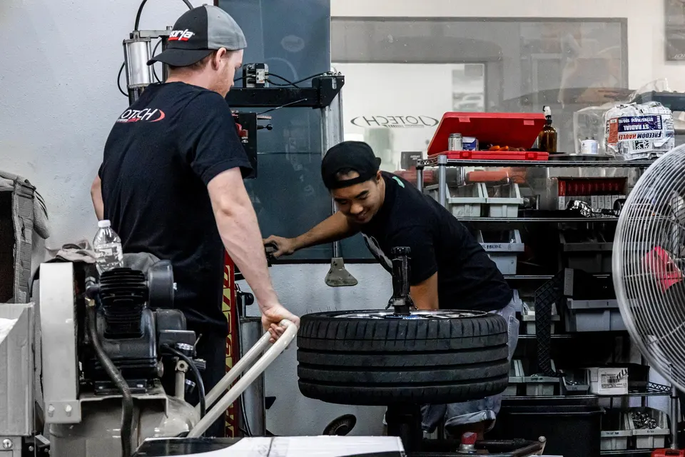 Mechanics working on a tire in a performance tuning shop, using a tire mounting machine.