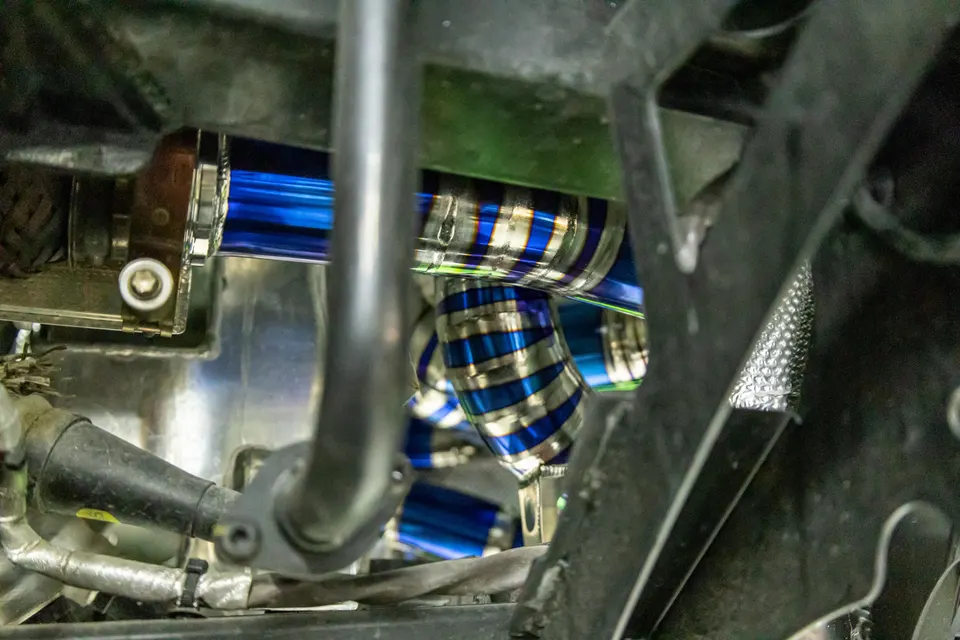 Close-up of custom blue and silver titanium boost piping in a high-performance car's engine bay.