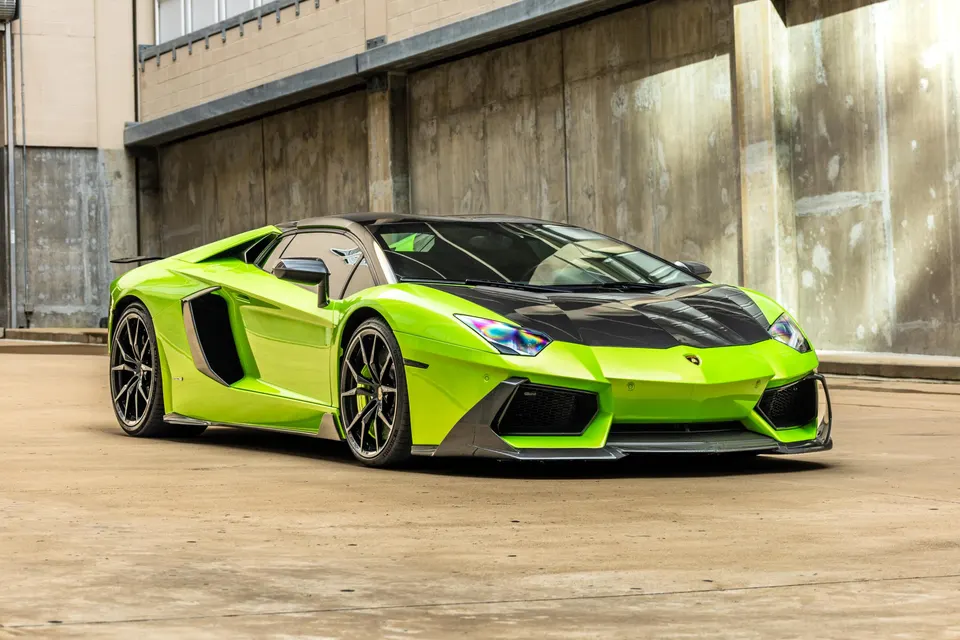 Bright green Lamborghini Aventador with carbon fiber hood, front splitter, side skirts, and rear wing parked in an urban setting.