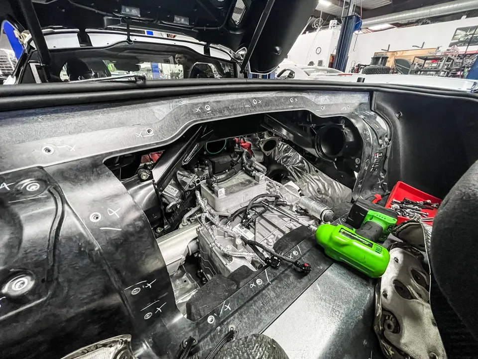 A C8 Corvette mid-engine bay undergoing work in a performance tuning shop with tools visible during a build.