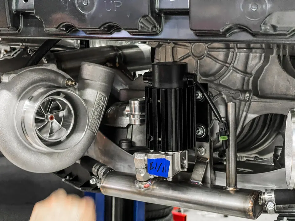 Close-up of a Precision Turbo turbocharger and custom boost piping installed in a high-performance engine bay.